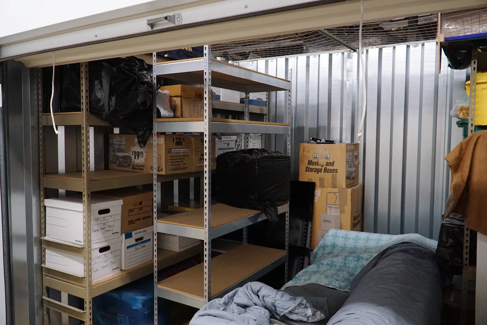 Interior of a climate-controlled self-storage unit with shelving, boxes, and a covered sofa.