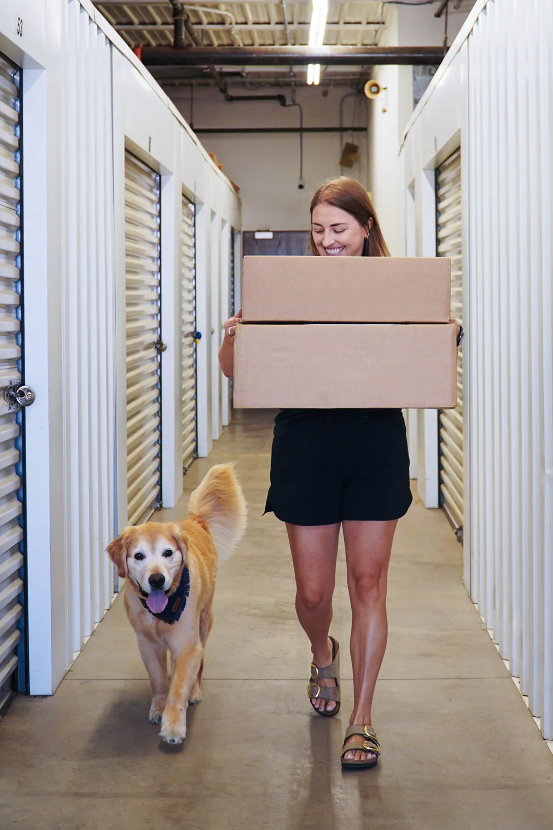 Golden retriever accompanies a woman carrying boxes at Store & Fetch on E. Benson Road.